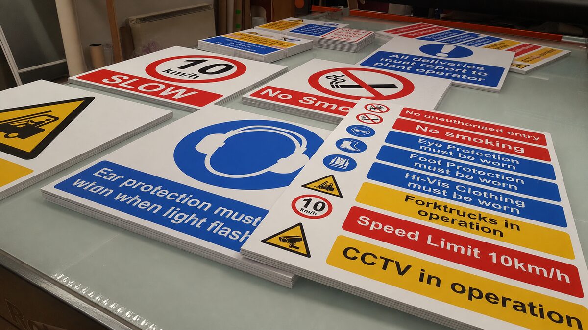 Freshly cut compliance and safety signs — mandatory PPE, prohibition, and warning signage